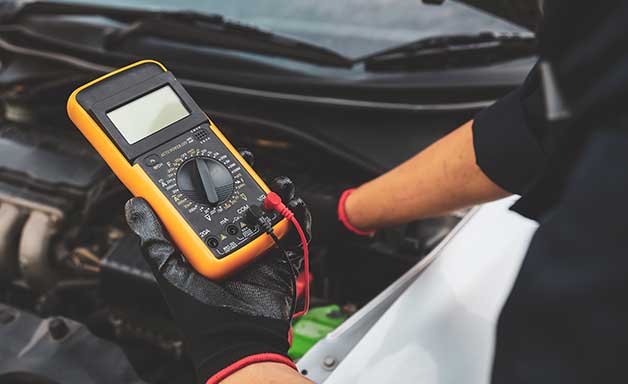Electrical technician car mechanic use voltmeter to check voltage battery low energy problem for car care service maintenance and re charger or jump start or change battery replacement.